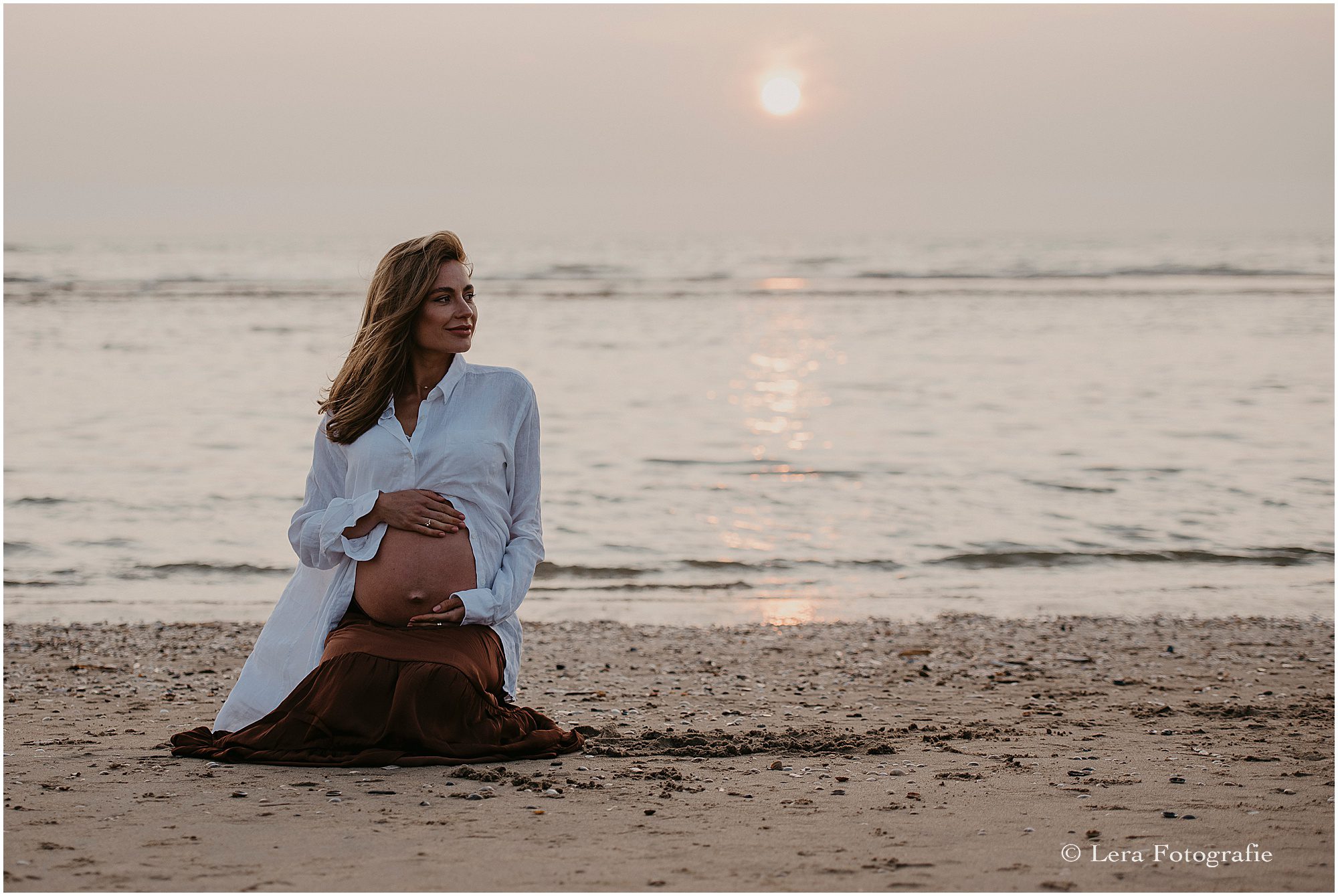 zwangerschapsfotoshoot op het strand met ondergaande zon